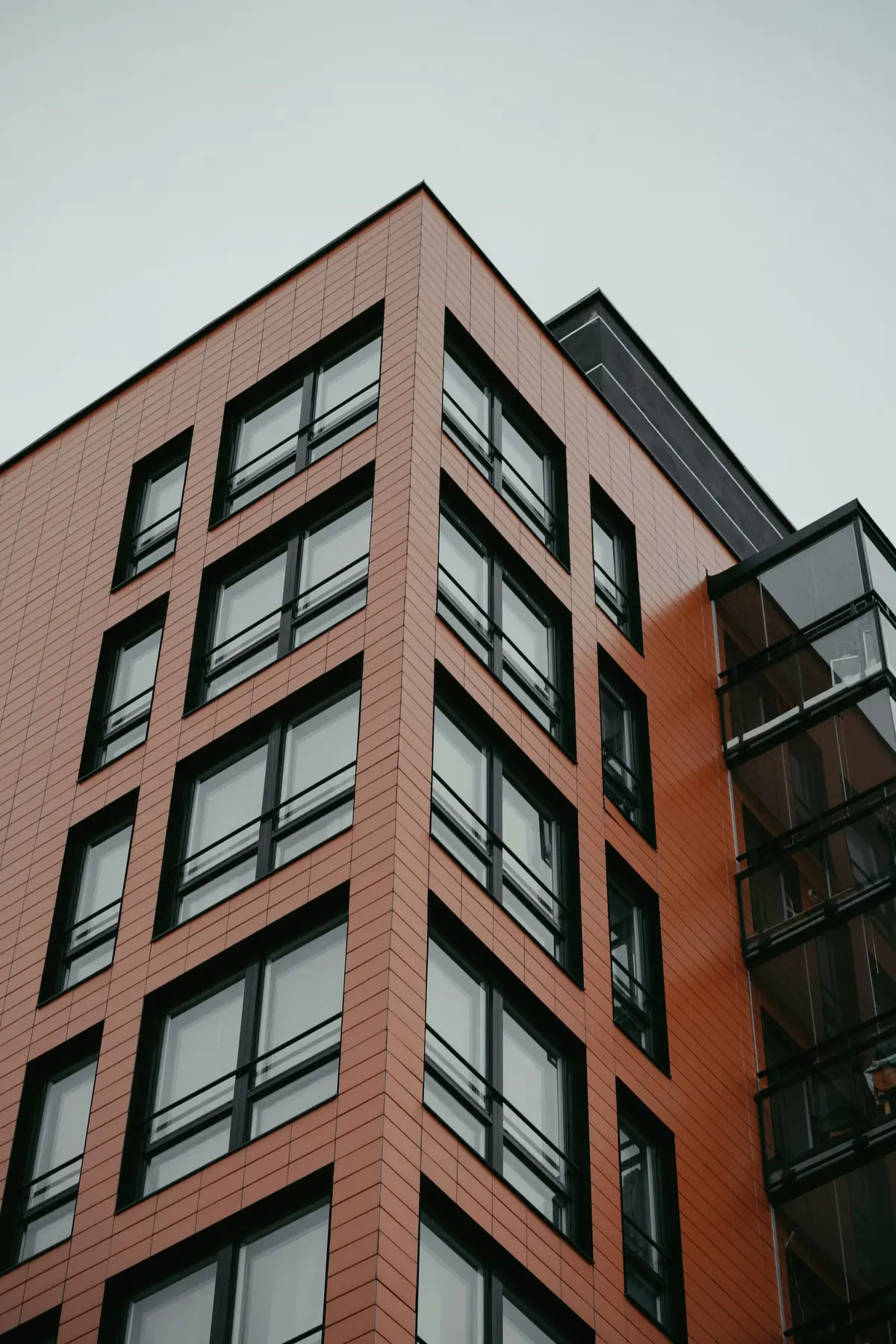 A brick mid-rise apartment building with large windows seen from below