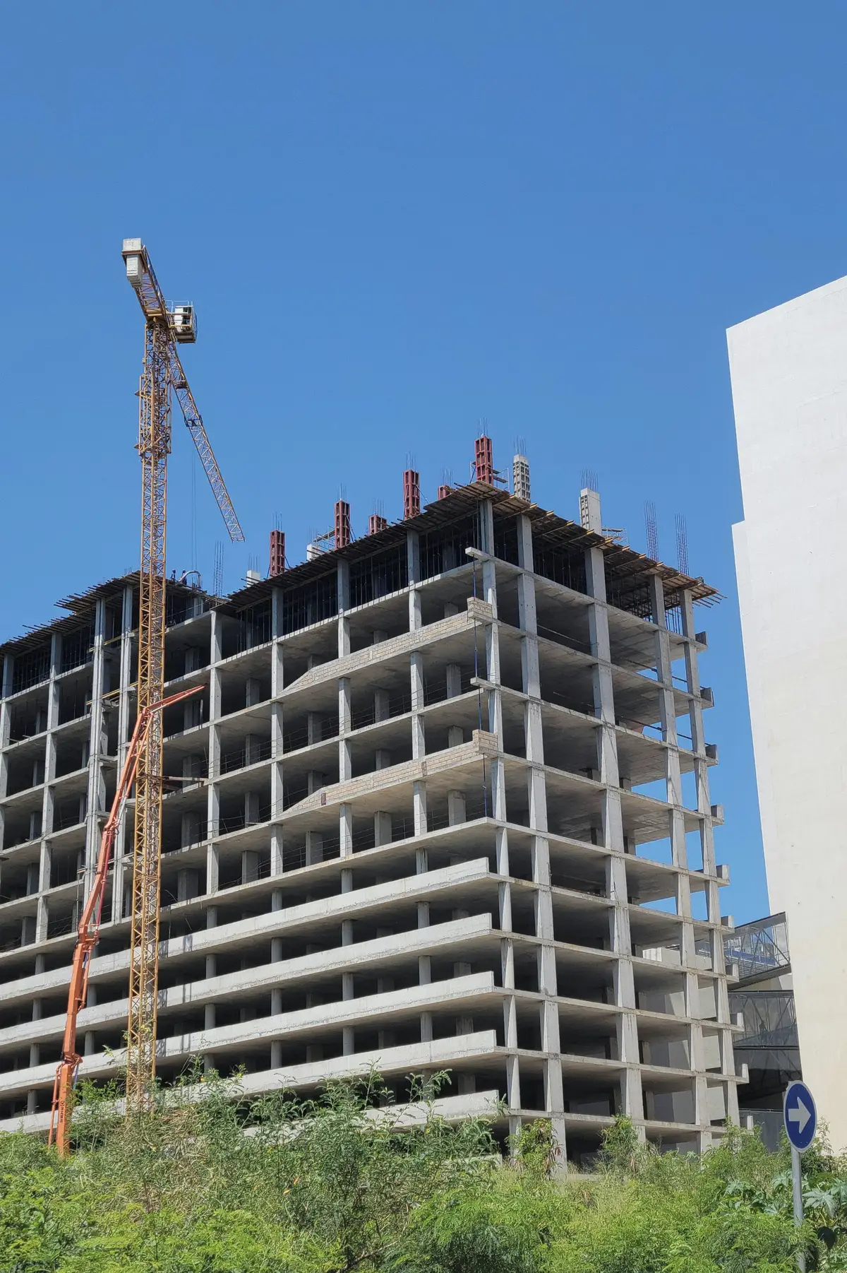 A concrete-frame residential building under construction with a tower crane