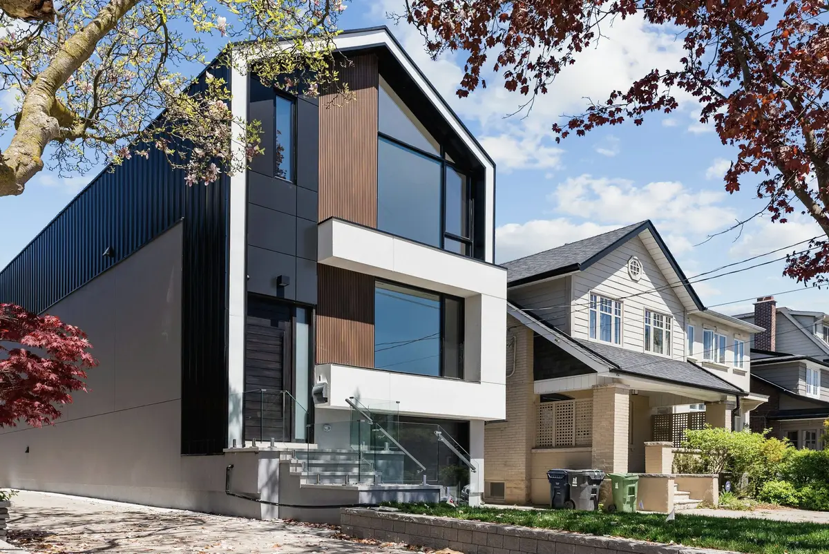 A contemporary dark-clad house beside traditional houses
