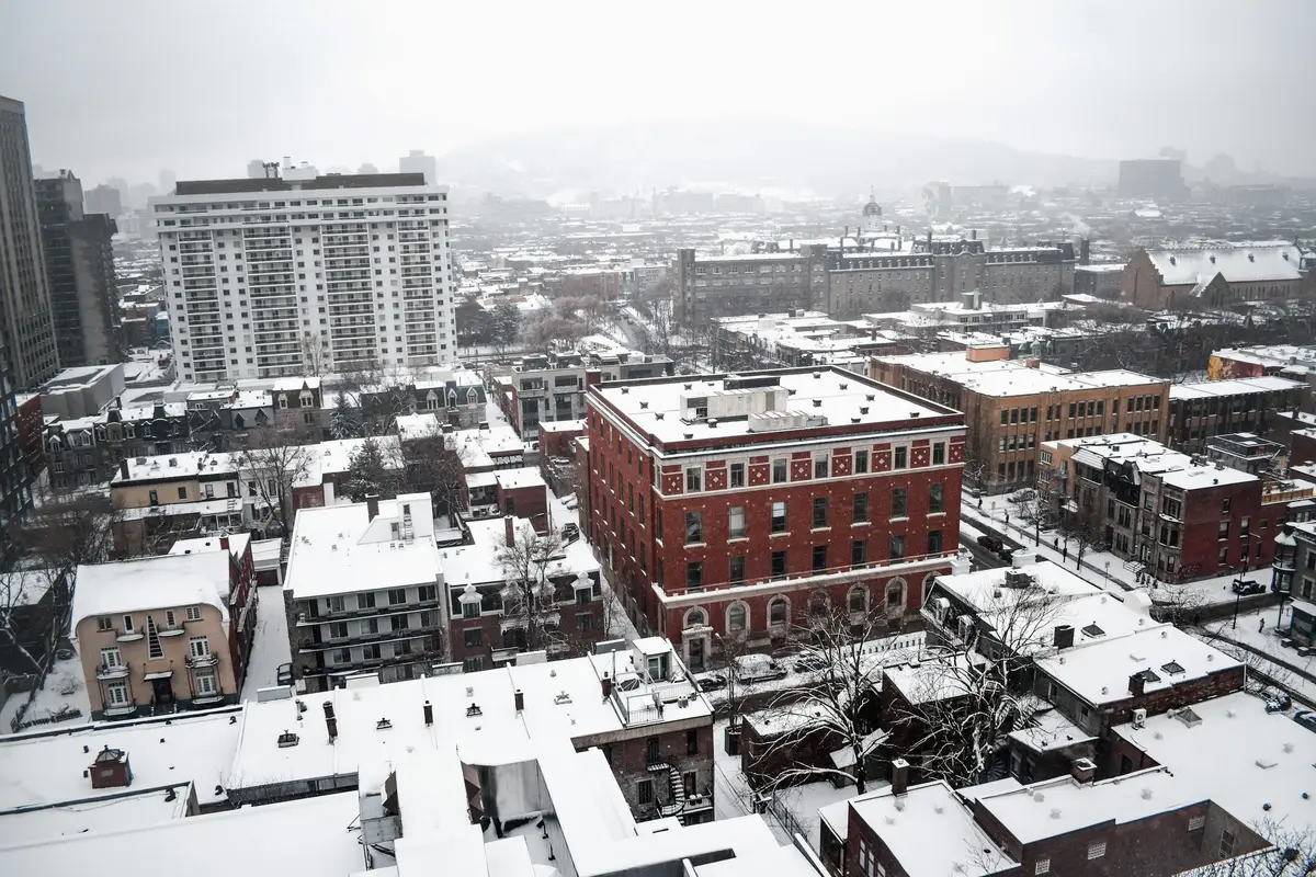 Rooftops of Montréal covered in snow, with brick buildings and towers in the distance