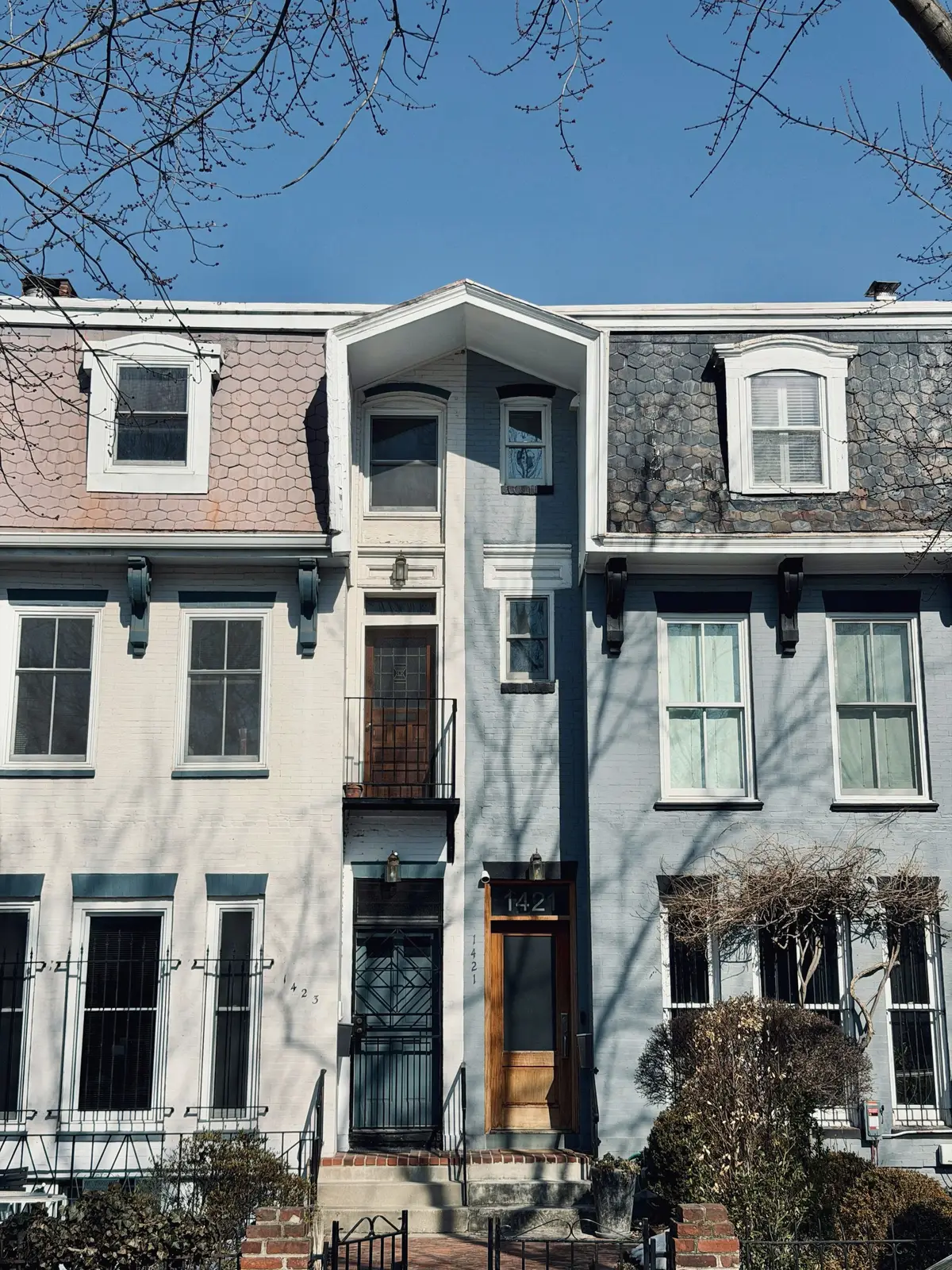 Row houses with mansard roofs and different facades under a clear sky
