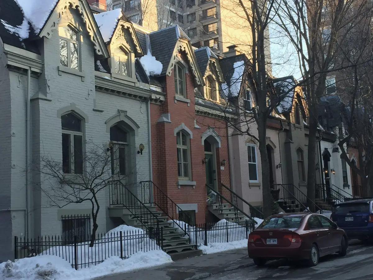 Greystone and brick row houses with front stairs after a snowfall